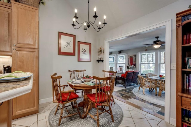 dining space with light tile patterned floors, ceiling fan with notable chandelier, and baseboards