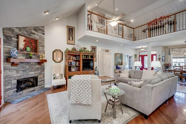 living room with a fireplace, high vaulted ceiling, ceiling fan, and wood finished floors