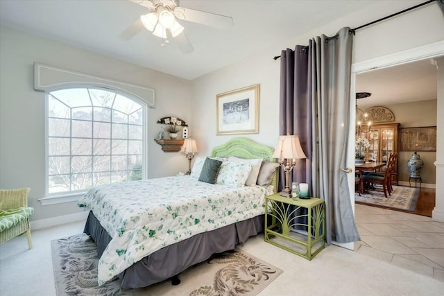 carpeted bedroom featuring tile patterned floors, baseboards, and a ceiling fan