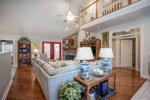 living room with a stone fireplace, ceiling fan, and wood finished floors