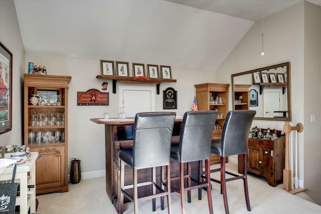 bar with baseboards, light carpet, indoor bar, and vaulted ceiling