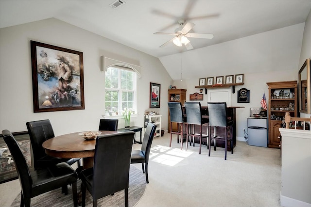 dining space featuring baseboards, visible vents, lofted ceiling, ceiling fan, and light colored carpet