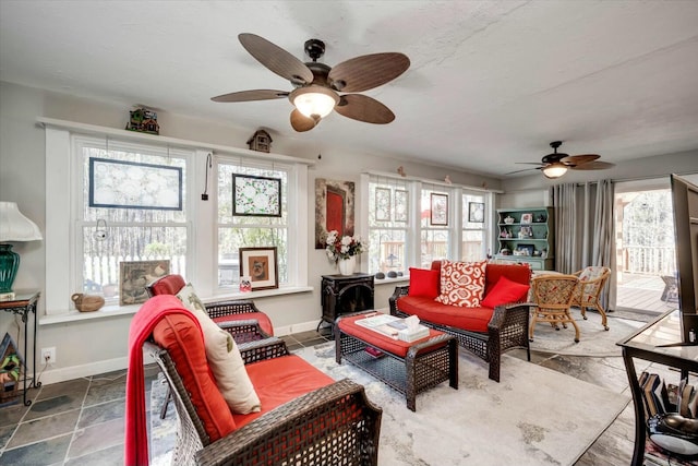 living area with stone finish floor, baseboards, and ceiling fan