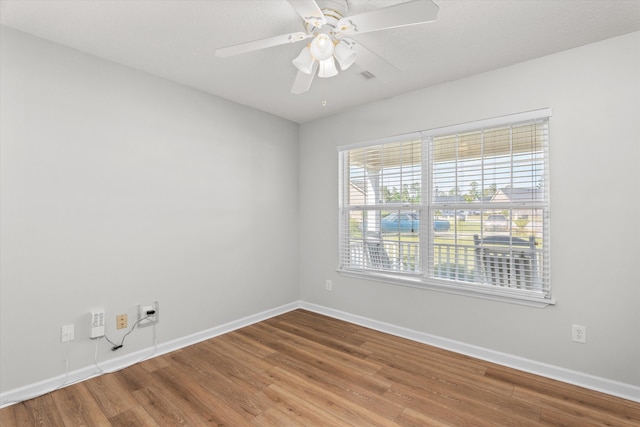 spare room with wood finished floors, visible vents, baseboards, and ceiling fan