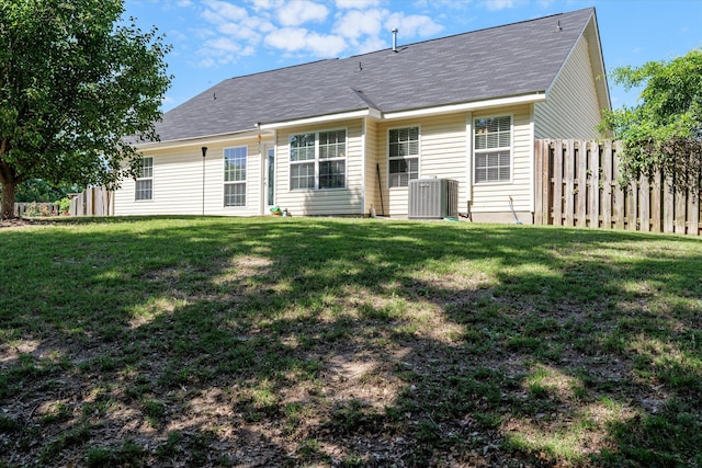 rear view of property with a lawn, central AC, a shingled roof, and fence