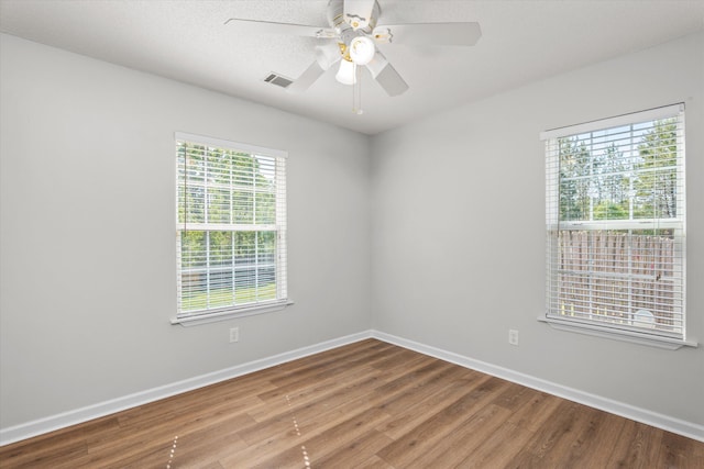 unfurnished room with ceiling fan, baseboards, visible vents, and wood finished floors