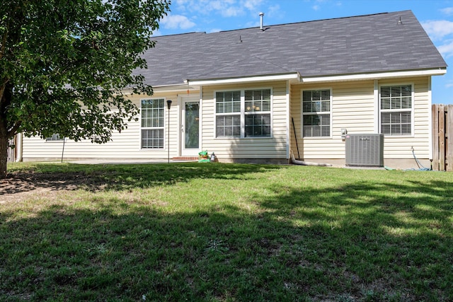 rear view of house with a yard, fence, and central AC