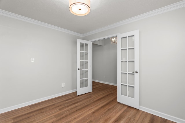 empty room featuring wood finished floors, french doors, baseboards, and ornamental molding