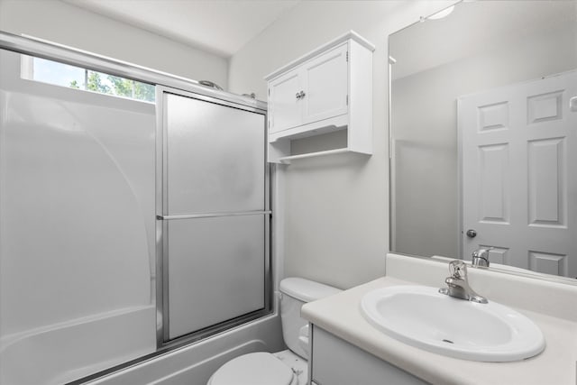 bathroom with toilet, vanity, and combined bath / shower with glass door