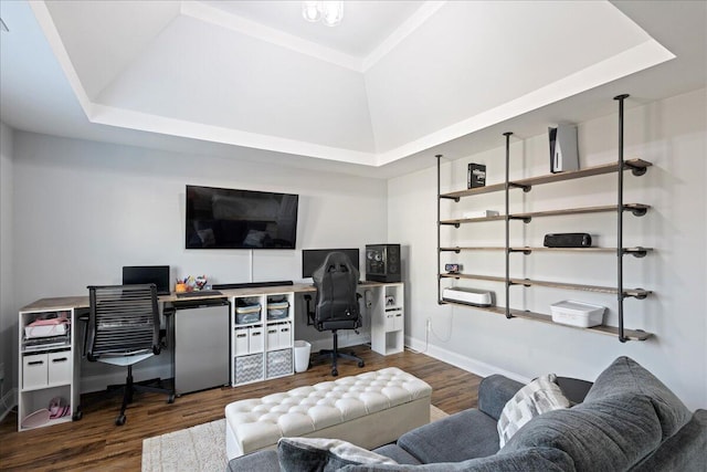 office space with a tray ceiling and dark wood-type flooring