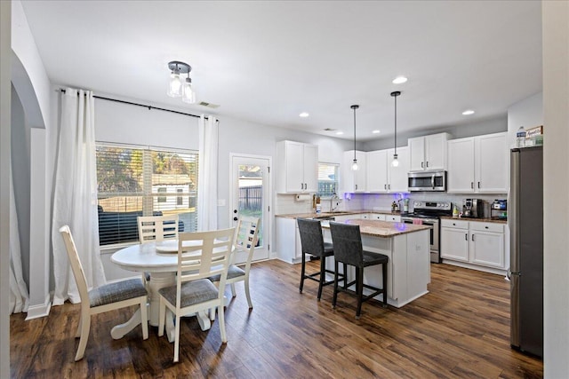 kitchen featuring stainless steel appliances, sink, white cabinets, a kitchen island, and hanging light fixtures