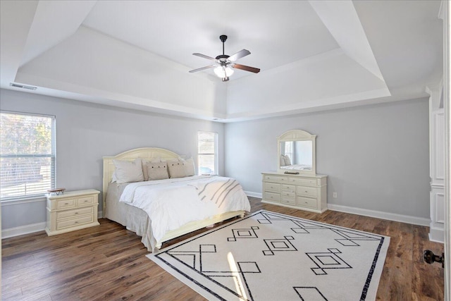 bedroom featuring ceiling fan, a raised ceiling, and dark wood-type flooring