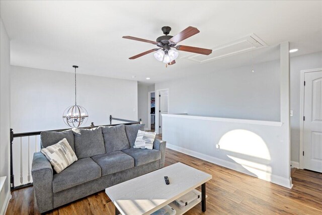 living room featuring ceiling fan with notable chandelier and hardwood / wood-style flooring