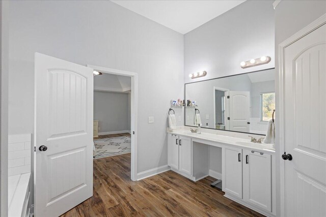 bathroom featuring hardwood / wood-style flooring, vanity, and vaulted ceiling