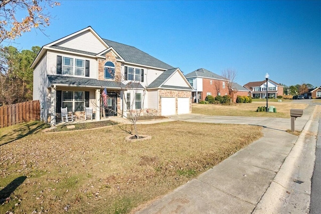 view of front of house featuring covered porch, a front yard, and a garage