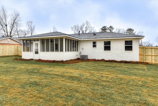 back of property with a sunroom, a yard, and central AC