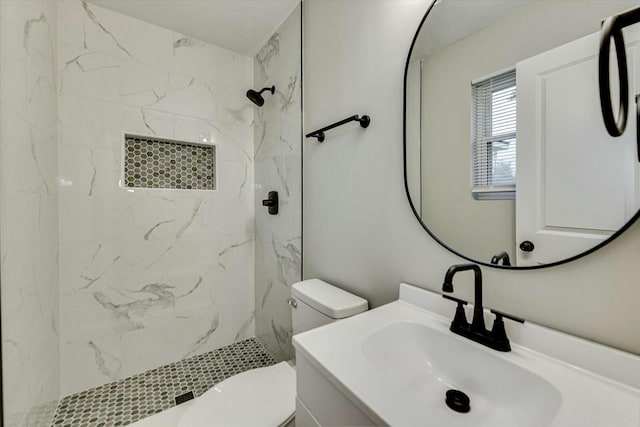 bathroom featuring vanity, tiled shower, and toilet