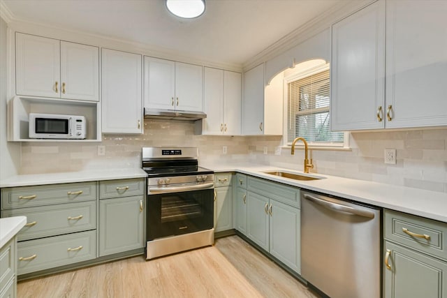 kitchen featuring stainless steel appliances, sink, white cabinets, and light wood-type flooring