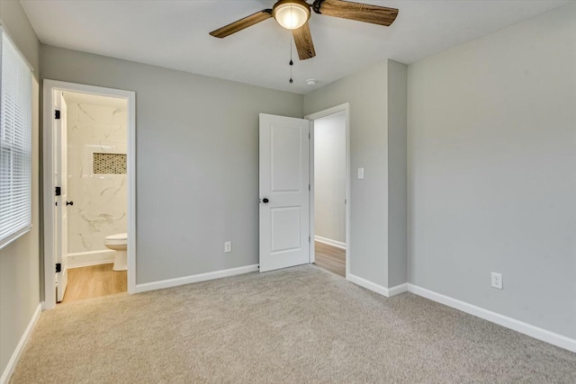 unfurnished bedroom with ceiling fan, light colored carpet, and ensuite bath