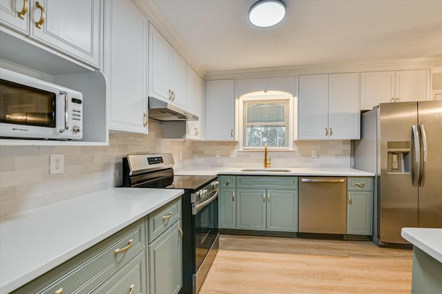 kitchen with sink, white cabinetry, light wood-type flooring, appliances with stainless steel finishes, and backsplash