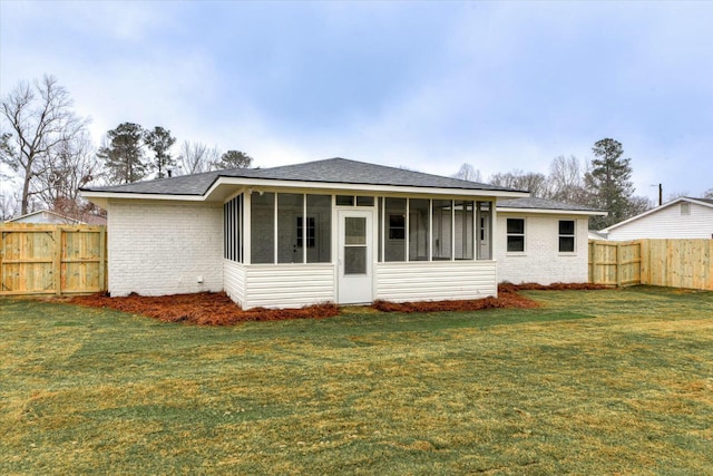 rear view of house with a lawn and a sunroom