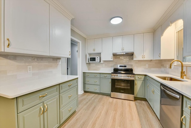 kitchen featuring sink, crown molding, light wood-type flooring, appliances with stainless steel finishes, and white cabinets