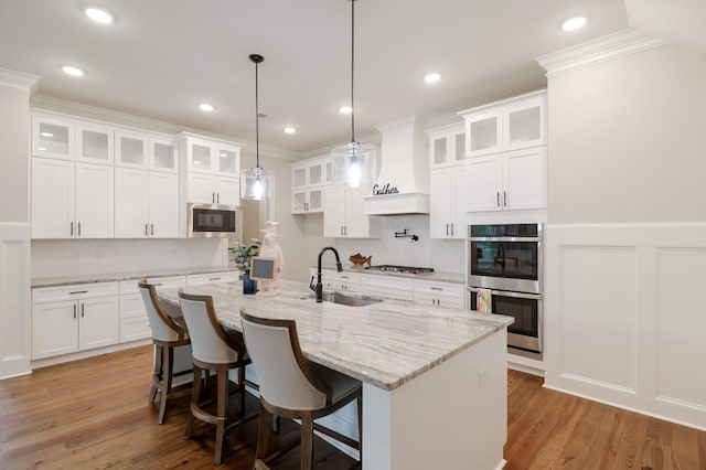 477 Rivernorth Dr, North Augusta, SC 29841 - kitchen featuring stainless steel appliances, crown molding, custom exhaust hood, white cabinetry, and a kitchen bar