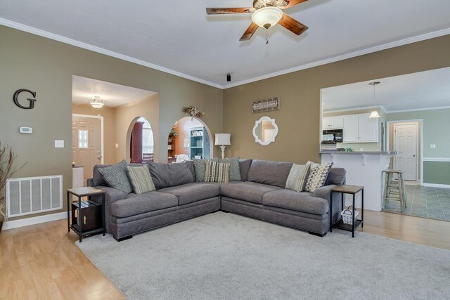 living room featuring ceiling fan, light wood-type flooring, and ornamental molding