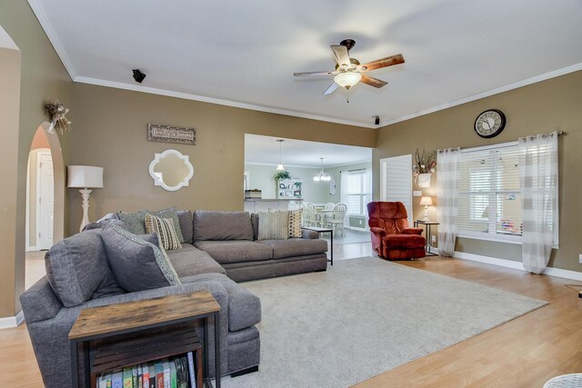 living room featuring hardwood / wood-style floors, ceiling fan with notable chandelier, and ornamental molding