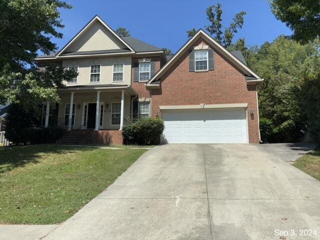 view of front facade with brick siding, a porch, concrete driveway, a front yard, and an attached garage