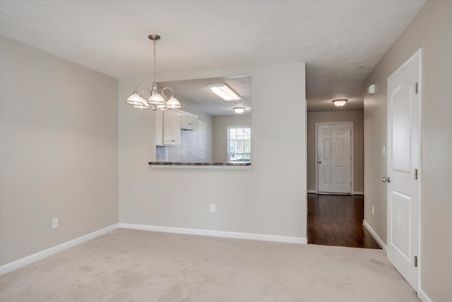 empty room featuring carpet and an inviting chandelier