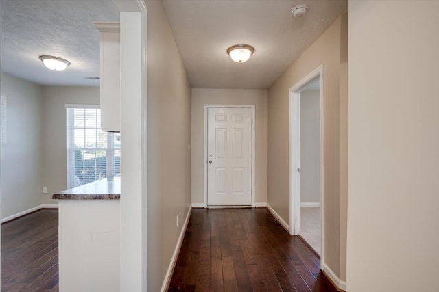 hallway with dark hardwood / wood-style flooring and a textured ceiling