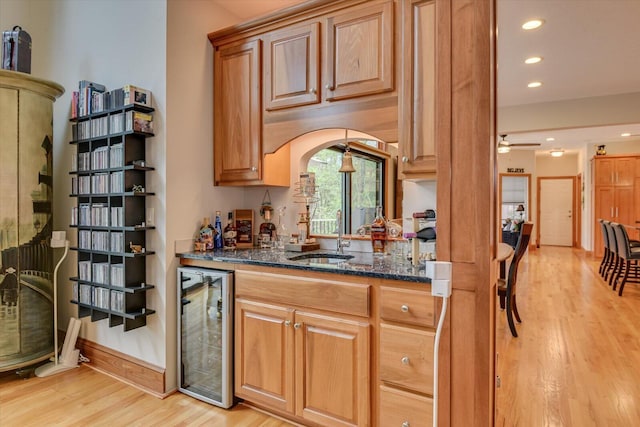 207 Rosewood Ln, Mccormick, SC 29835 - kitchen featuring beverage cooler, a sink, light wood-type flooring, dark stone counters, and ceiling fan