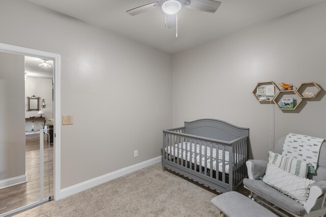 bedroom with ceiling fan, a nursery area, and light carpet