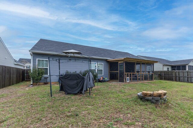 rear view of house featuring a sunroom, a fire pit, a gazebo, and a lawn