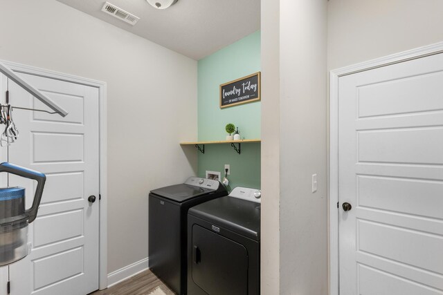 clothes washing area featuring wood-type flooring and washing machine and dryer