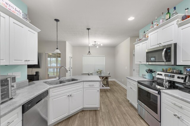 kitchen with white cabinetry, sink, stainless steel appliances, light hardwood / wood-style floors, and decorative light fixtures