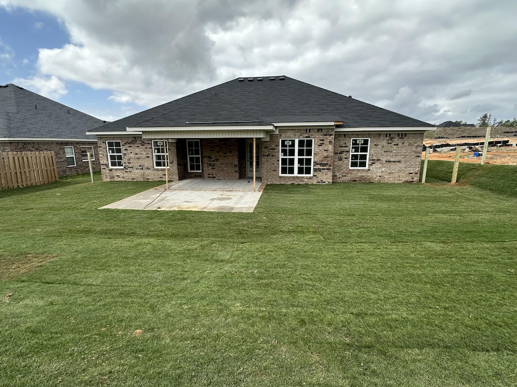 back of house with a yard, fence, brick siding, and a patio