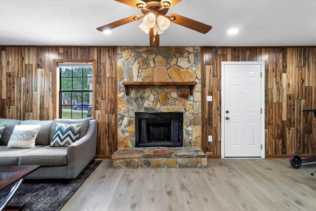 2726 Cardigan Ct, Hephzibah, GA 30815 - living area with wooden walls, a ceiling fan, wood finished floors, and a stone fireplace