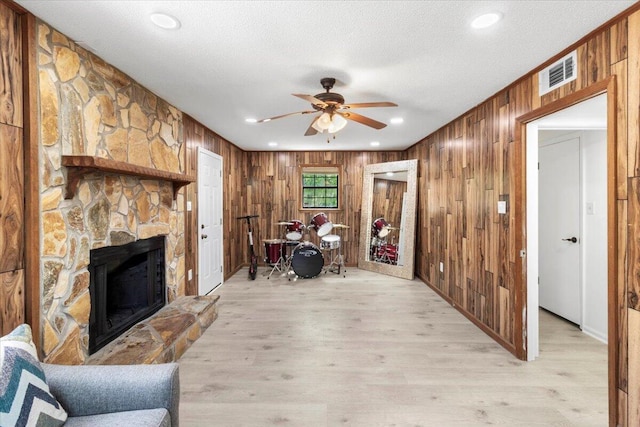 2726 Cardigan Ct, Hephzibah, GA 30815 - living room featuring wood walls, ceiling fan, light wood-style floors, a fireplace, and a textured ceiling