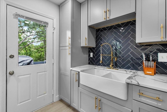 2726 Cardigan Ct, Hephzibah, GA 30815 - kitchen with tasteful backsplash, gray cabinetry, a sink, and light stone counters