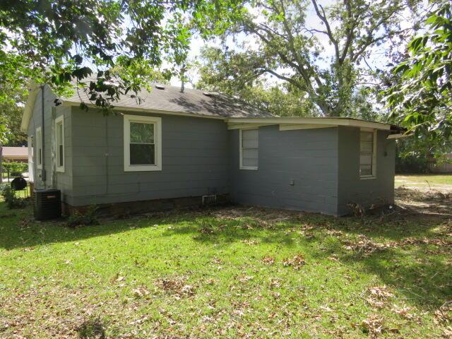 back of house featuring central AC unit and a lawn