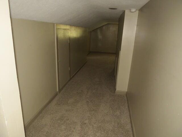 corridor with light colored carpet and vaulted ceiling