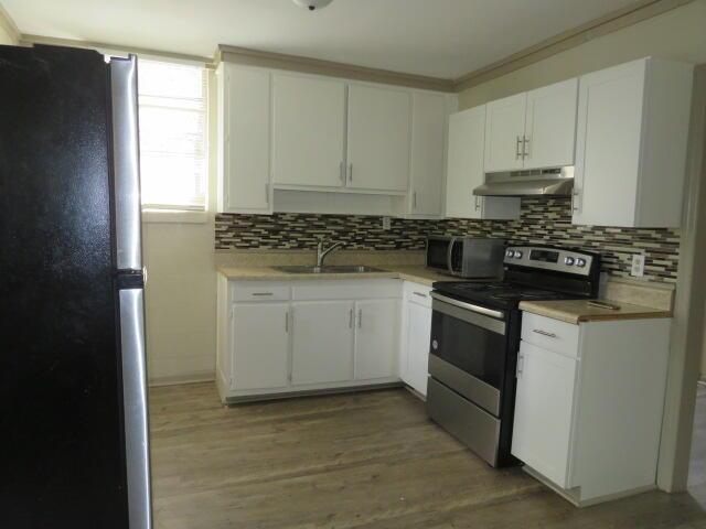 kitchen featuring tasteful backsplash, white cabinetry, sink, and stainless steel appliances