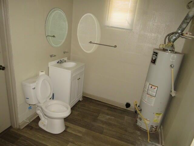 bathroom featuring toilet, vanity, gas water heater, and hardwood / wood-style flooring