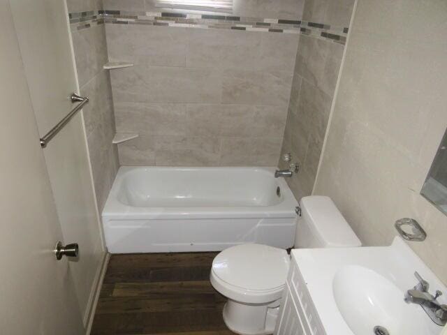 full bathroom with sink, wood-type flooring, tiled shower / bath combo, and toilet