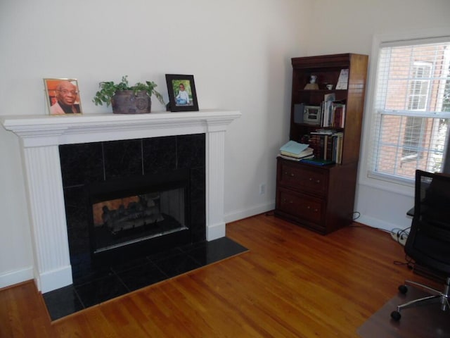 detailed view of a tile fireplace, wood finished floors, and baseboards