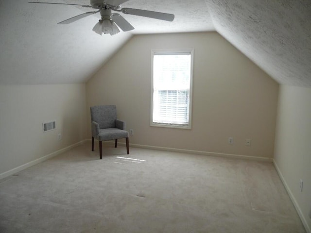 bonus room featuring ceiling fan, lofted ceiling, light colored carpet, and a textured ceiling