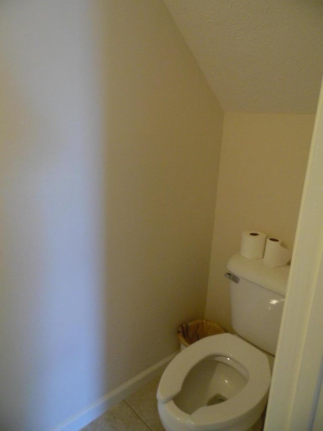 bathroom featuring tile patterned flooring, lofted ceiling, a textured ceiling, and toilet