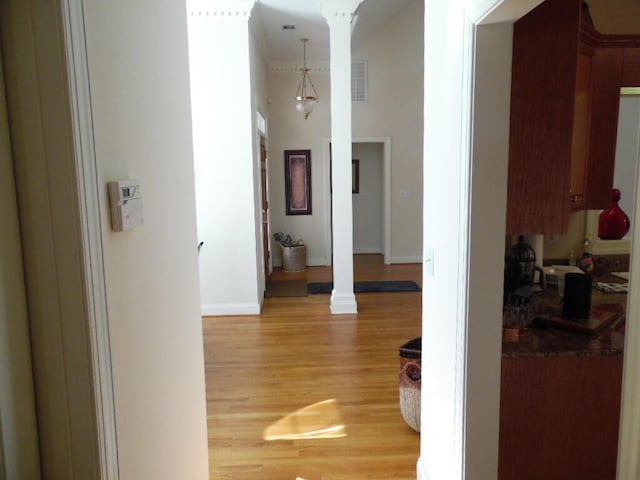 hall with wood-type flooring, decorative columns, and a high ceiling